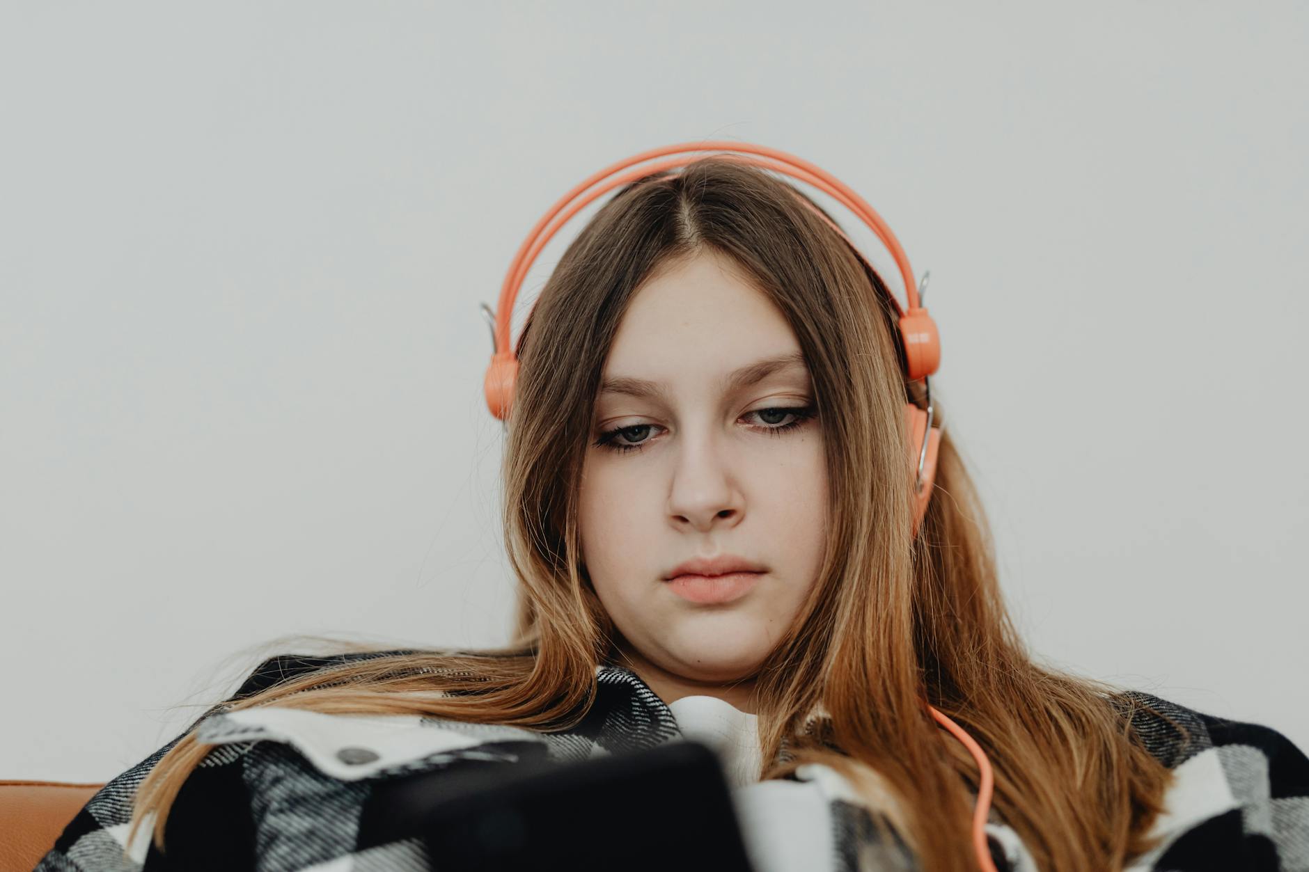 teenager wearing over-ear headphones while studying at home desk
